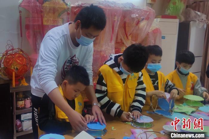 曹淑贞的外孙庄颖毅在教导小朋友们制作彩扎花灯。(受访者供图) 钟欣 摄