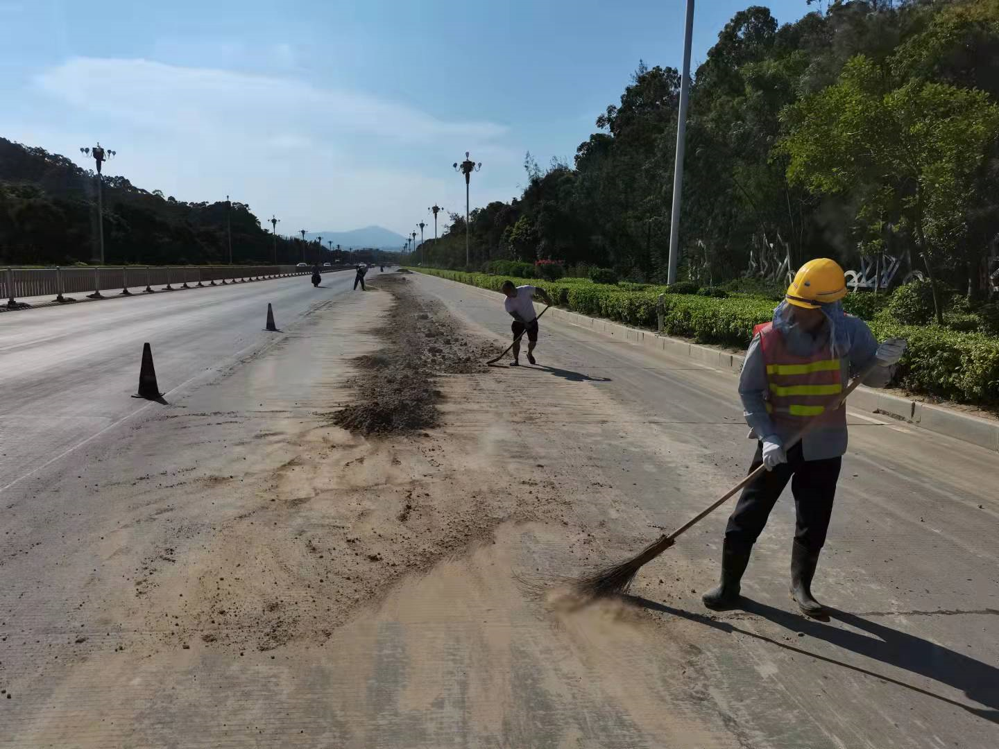 东山公路养护保员顶着烈日迅速清理路面泥沙,为群众出行保驾护航