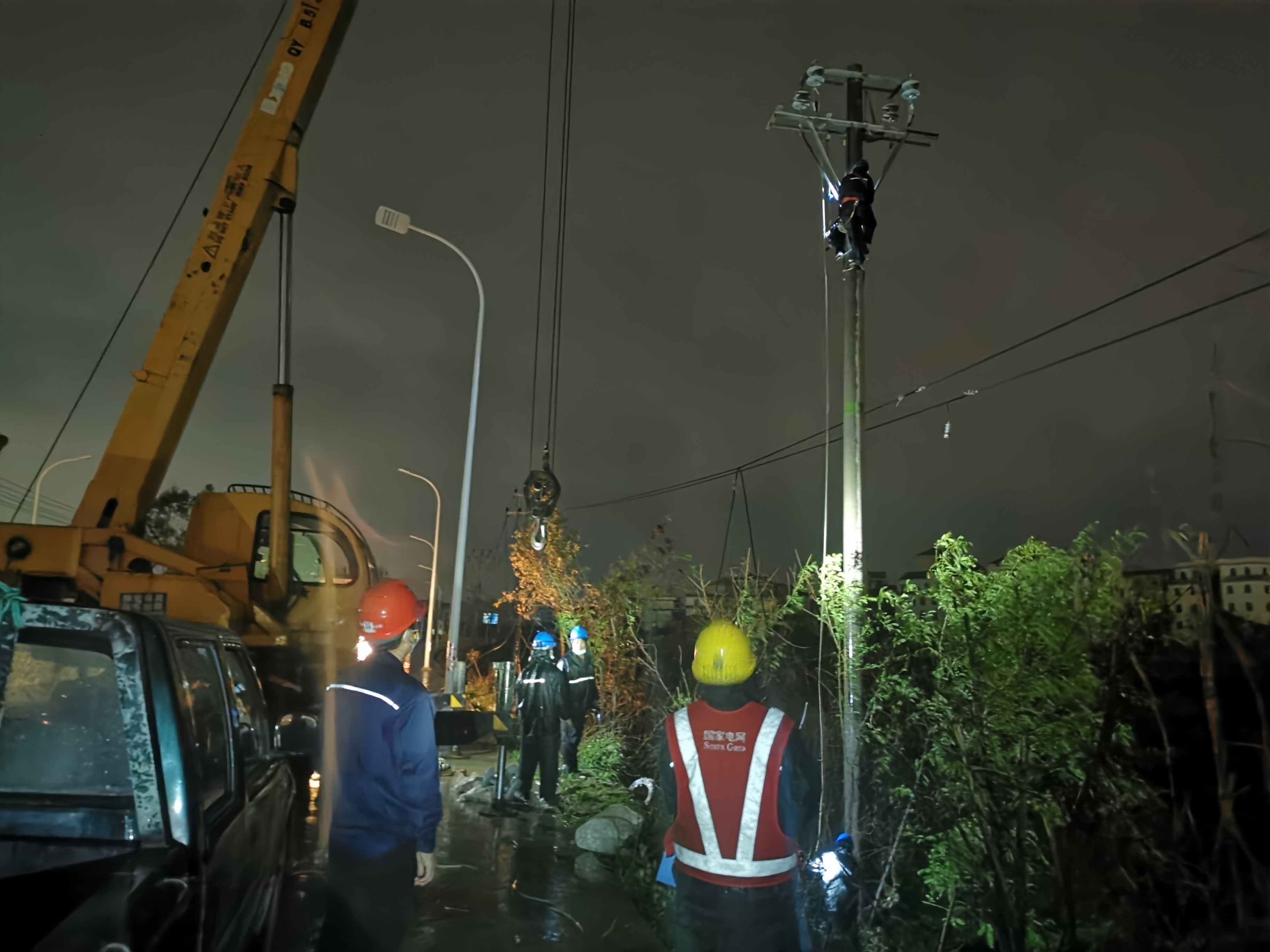 透过雨帘可以看到,抢修人员正有序移除受损电杆,立新杆,登杆组装金具